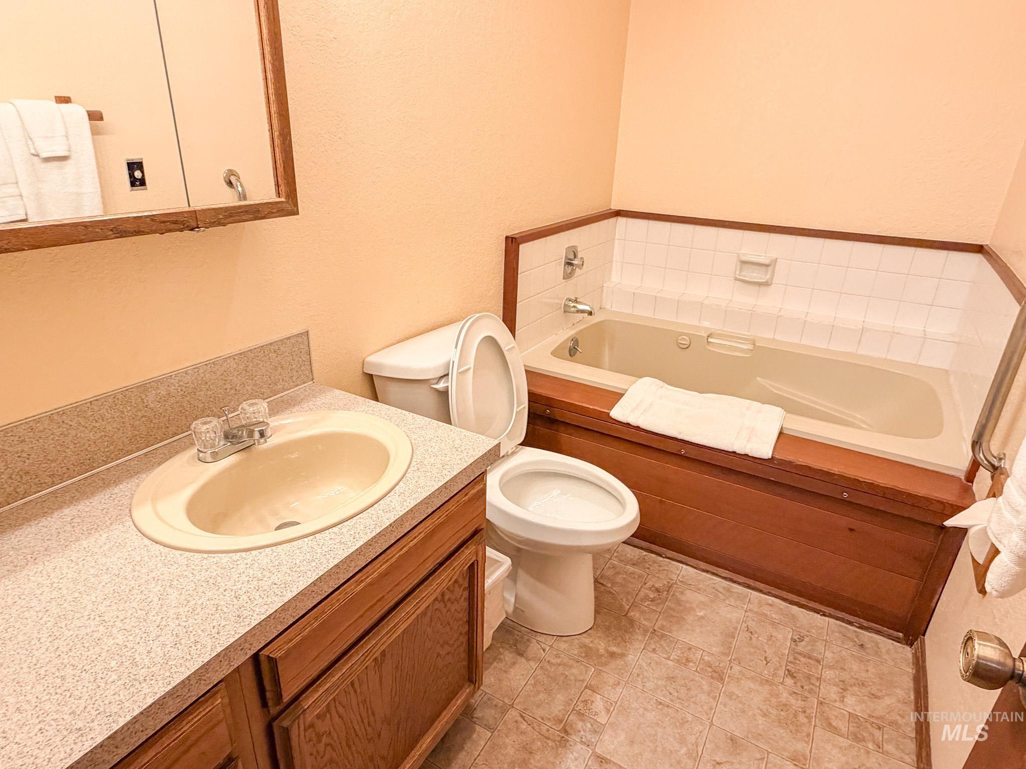 Bathroom with vanity, a textured wall, and a garden tub