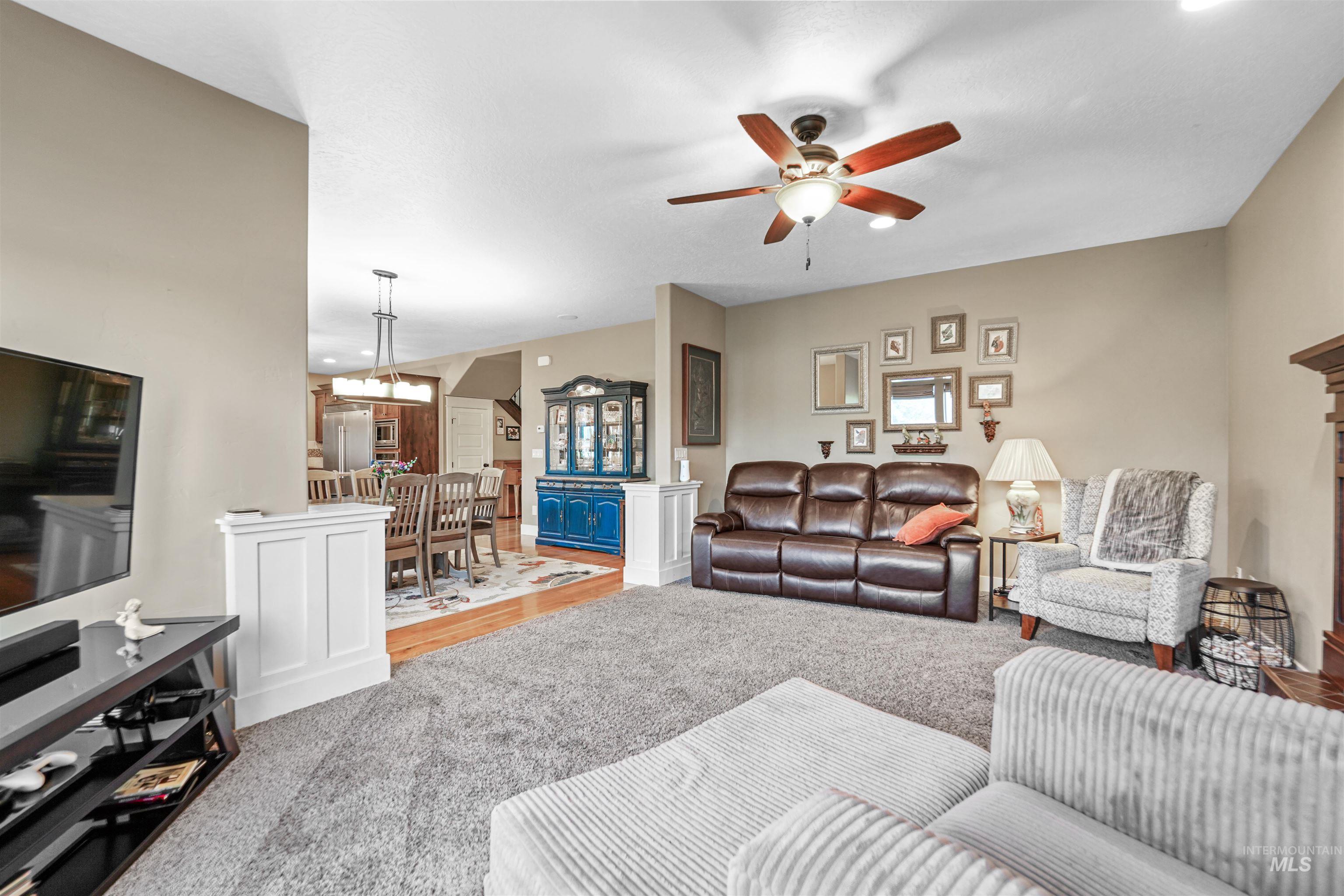 Living area with ceiling fan, wood finished floors, and carpet flooring