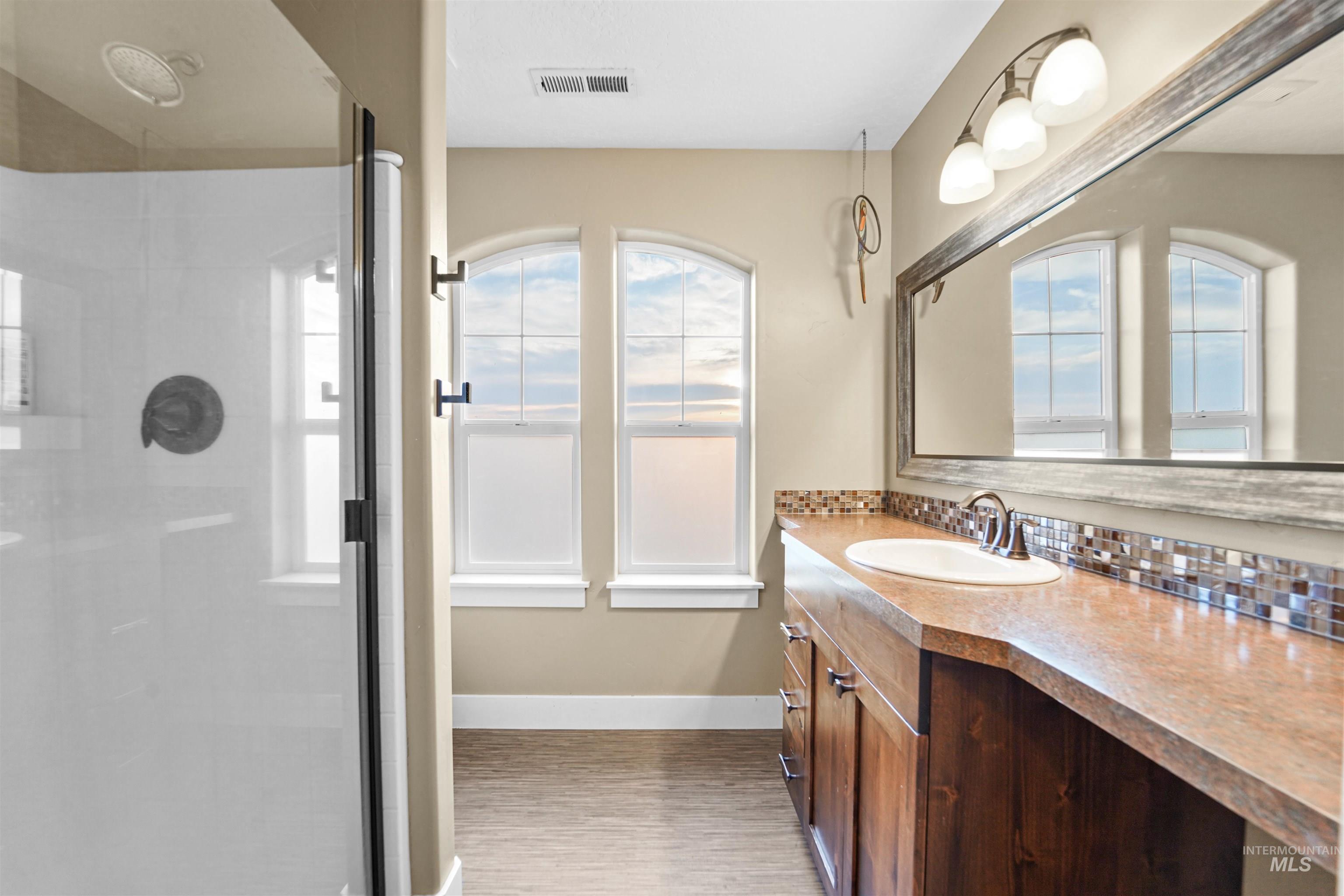Bathroom featuring vanity, a stall shower, and plenty of natural light
