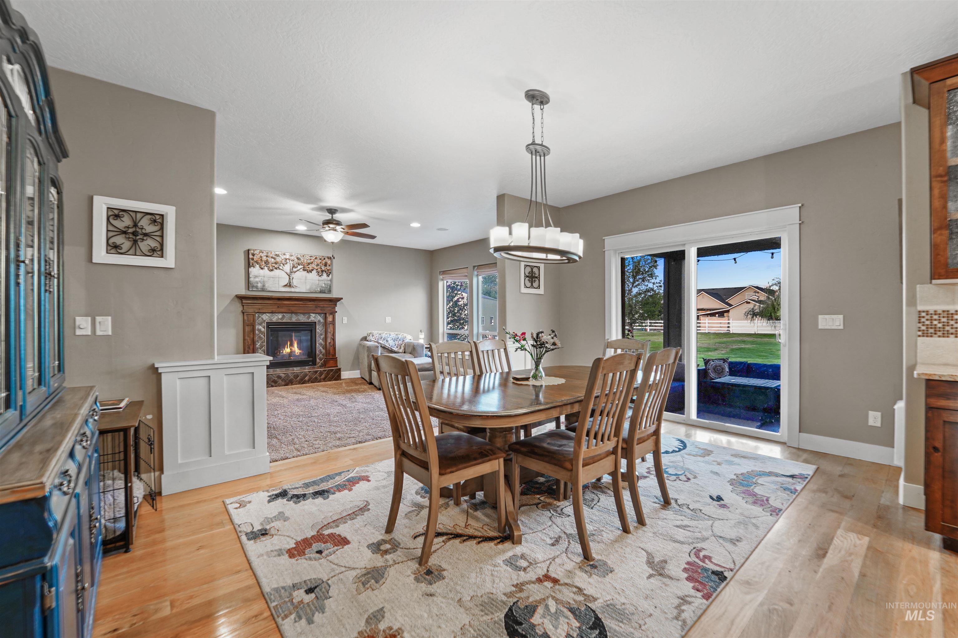 Dining area with a glass covered fireplace, light wood finished floors, ceiling fan, and recessed lighting
