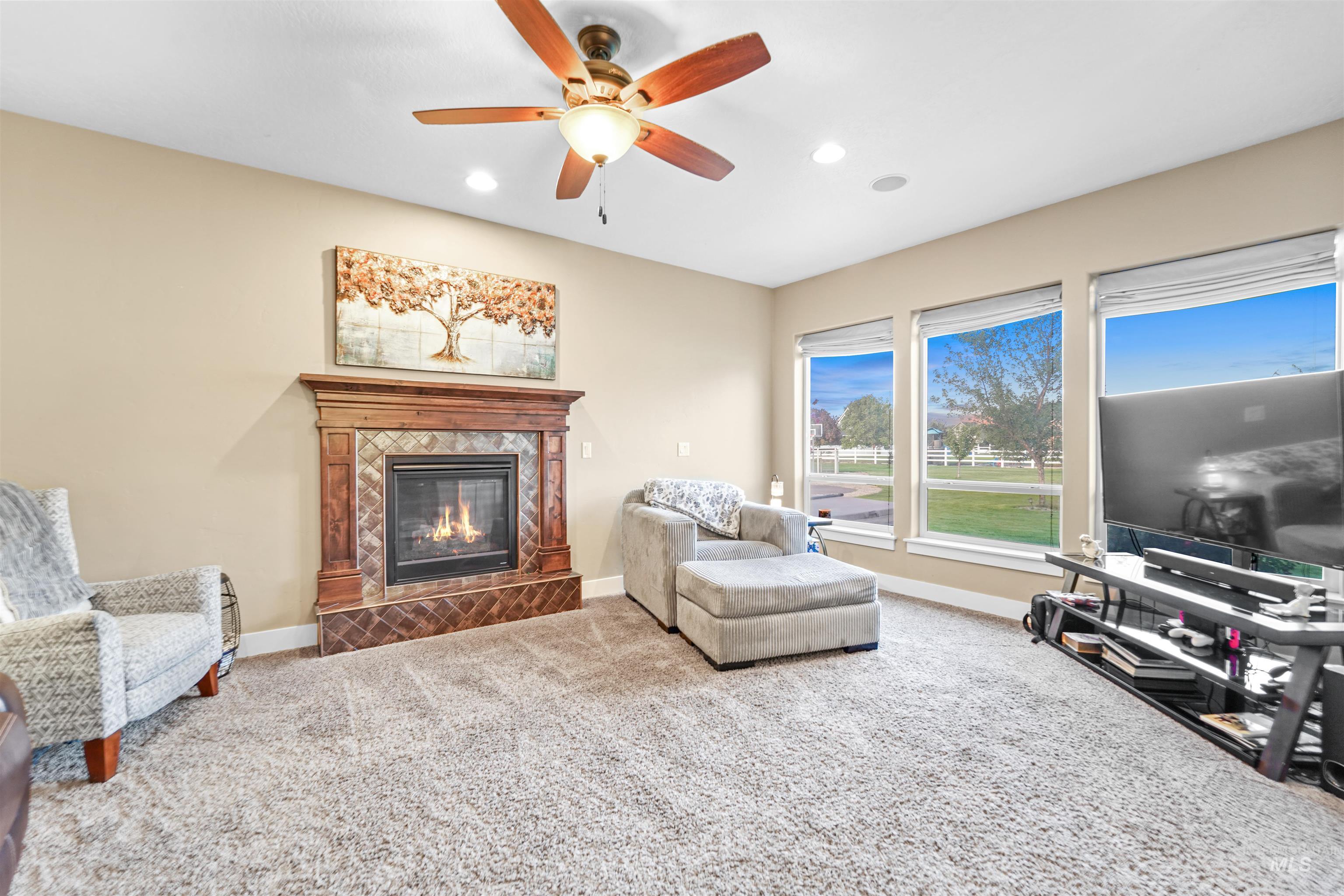 Living room with carpet, recessed lighting, a fireplace, and a ceiling fan
