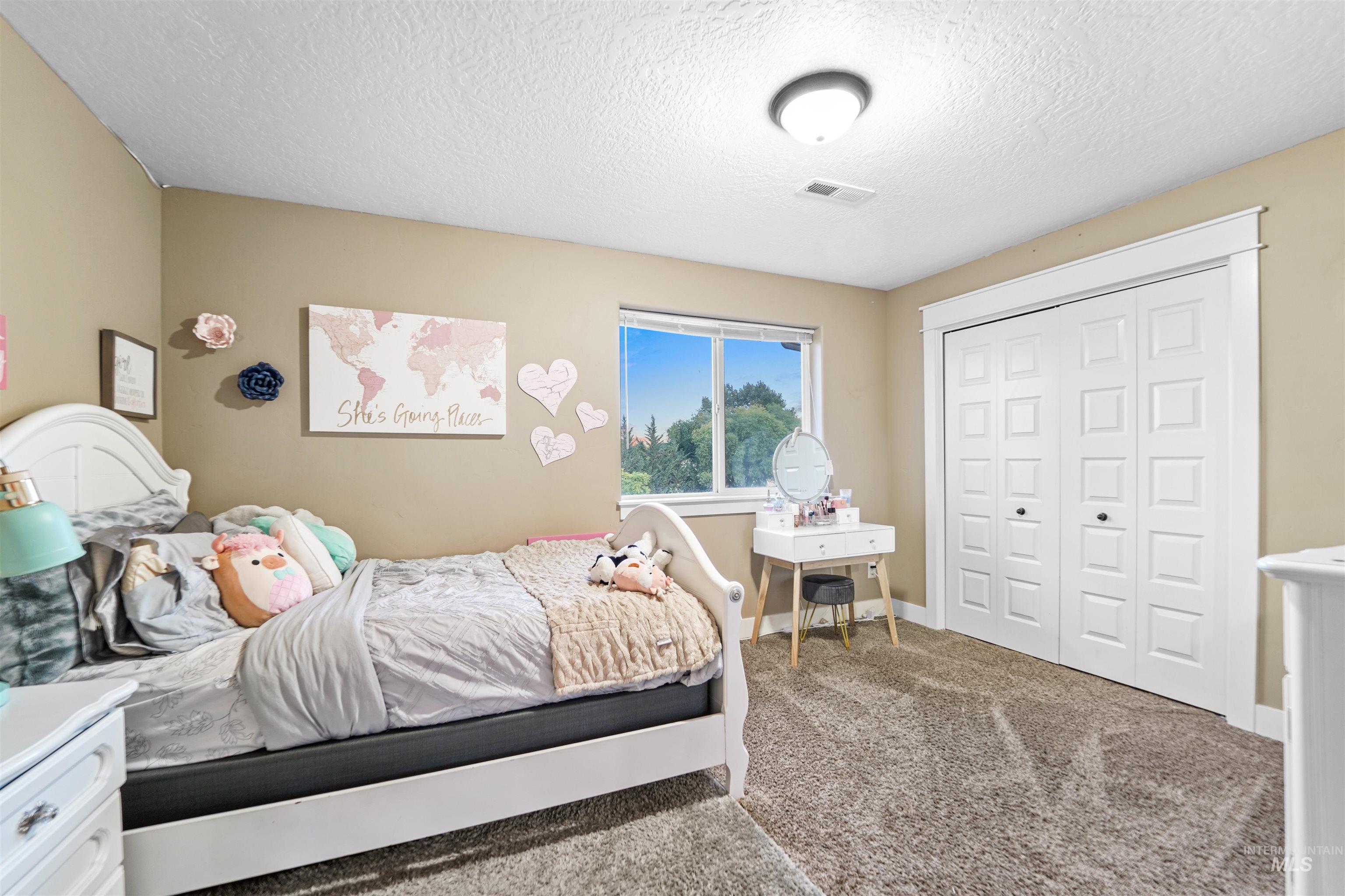 Bedroom featuring carpet flooring, a textured ceiling, and a closet