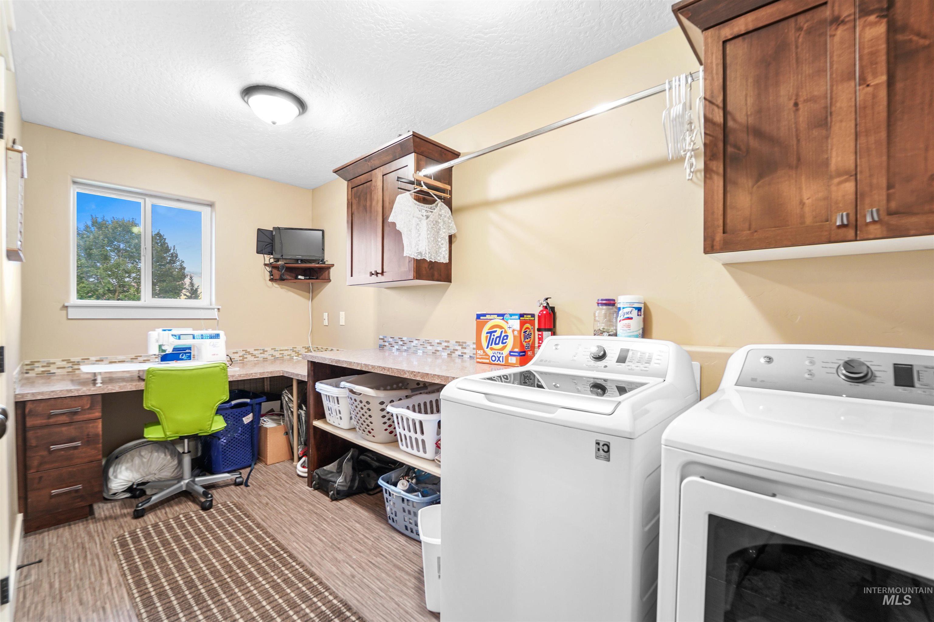 Laundry room featuring washing machine and dryer, cabinet space, a textured ceiling, and an office area