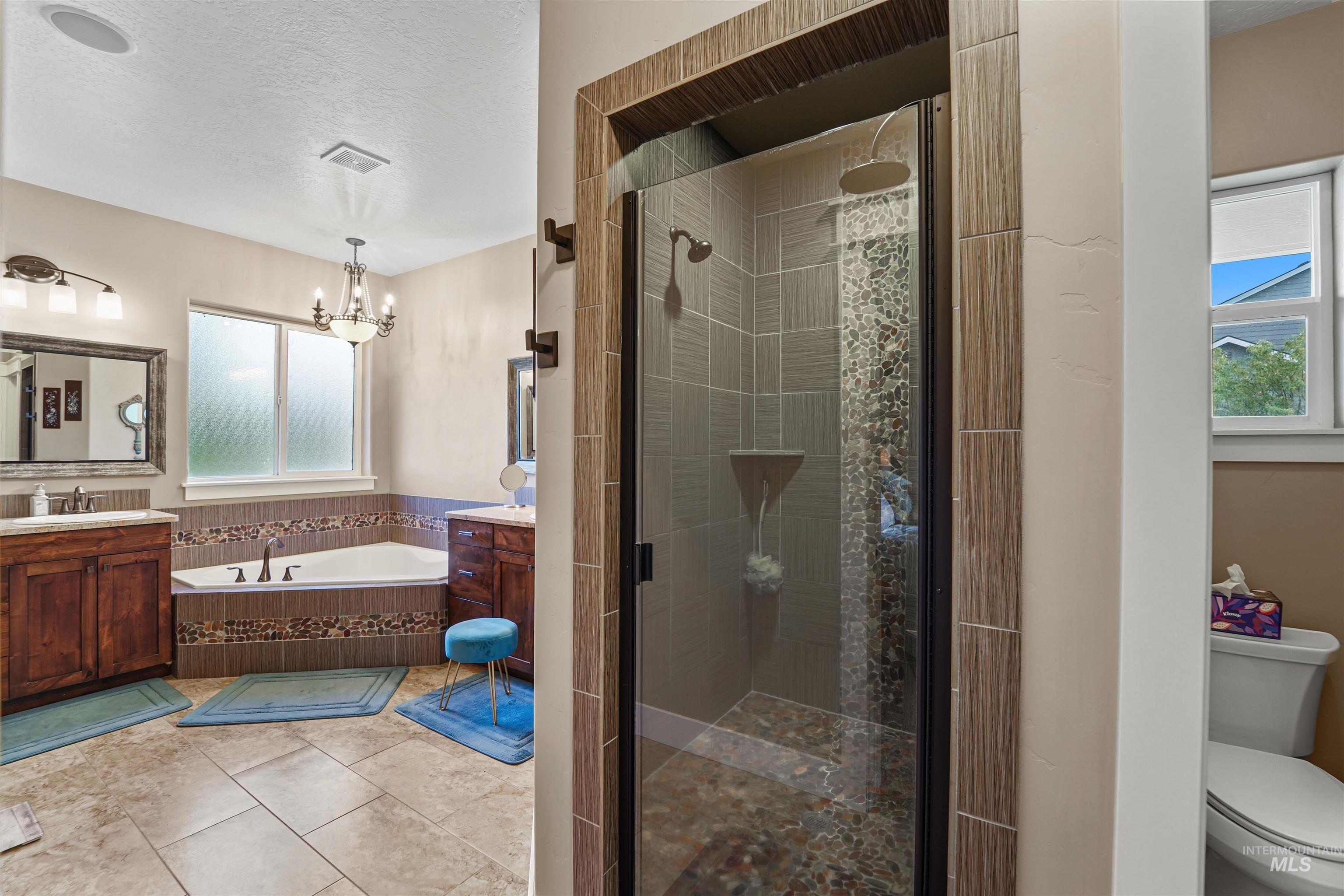 Bathroom with vanity, a garden tub, a shower stall, light tile patterned floors, and a textured ceiling