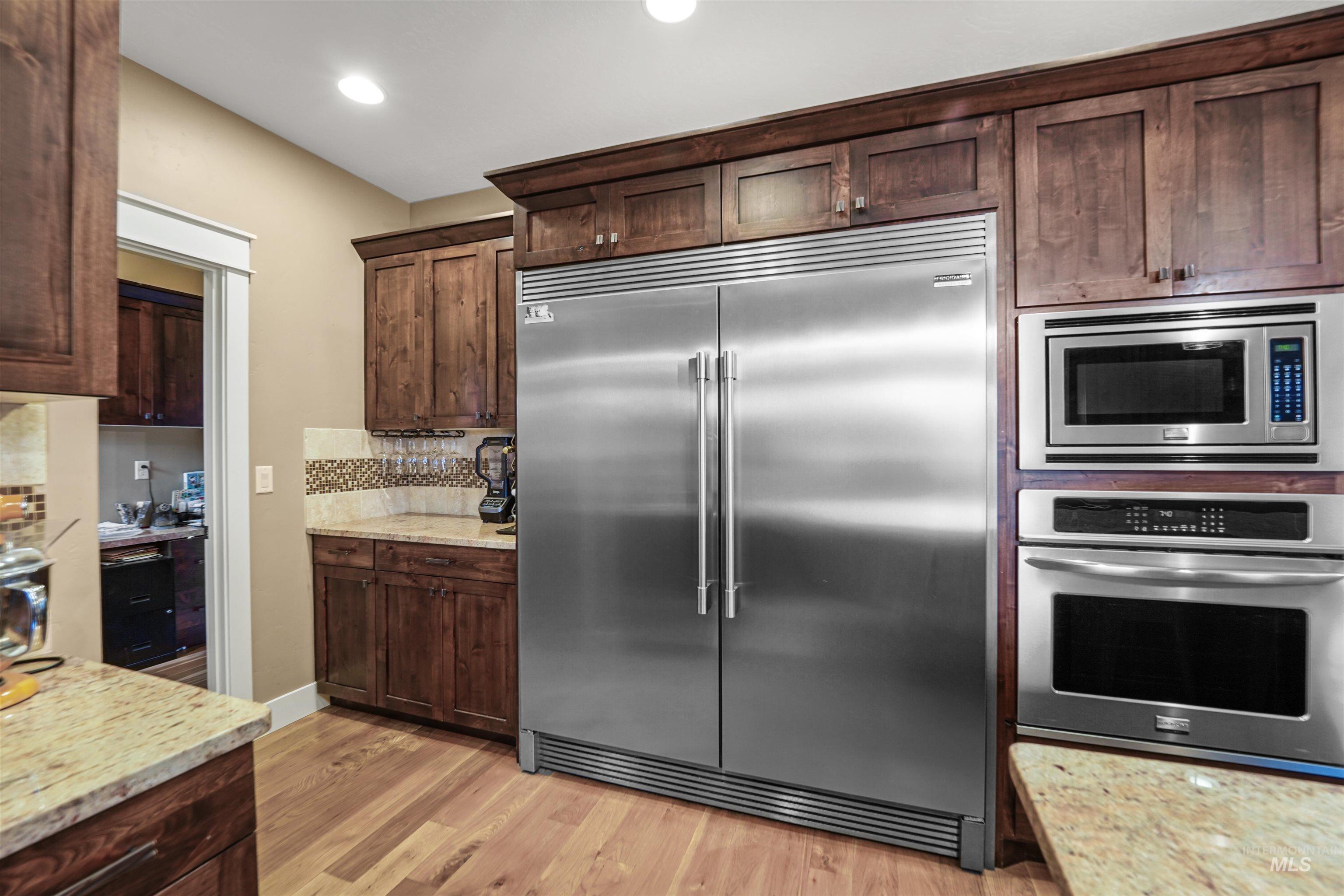 Kitchen featuring built in appliances, dark brown cabinets, light wood-style flooring, and recessed lighting