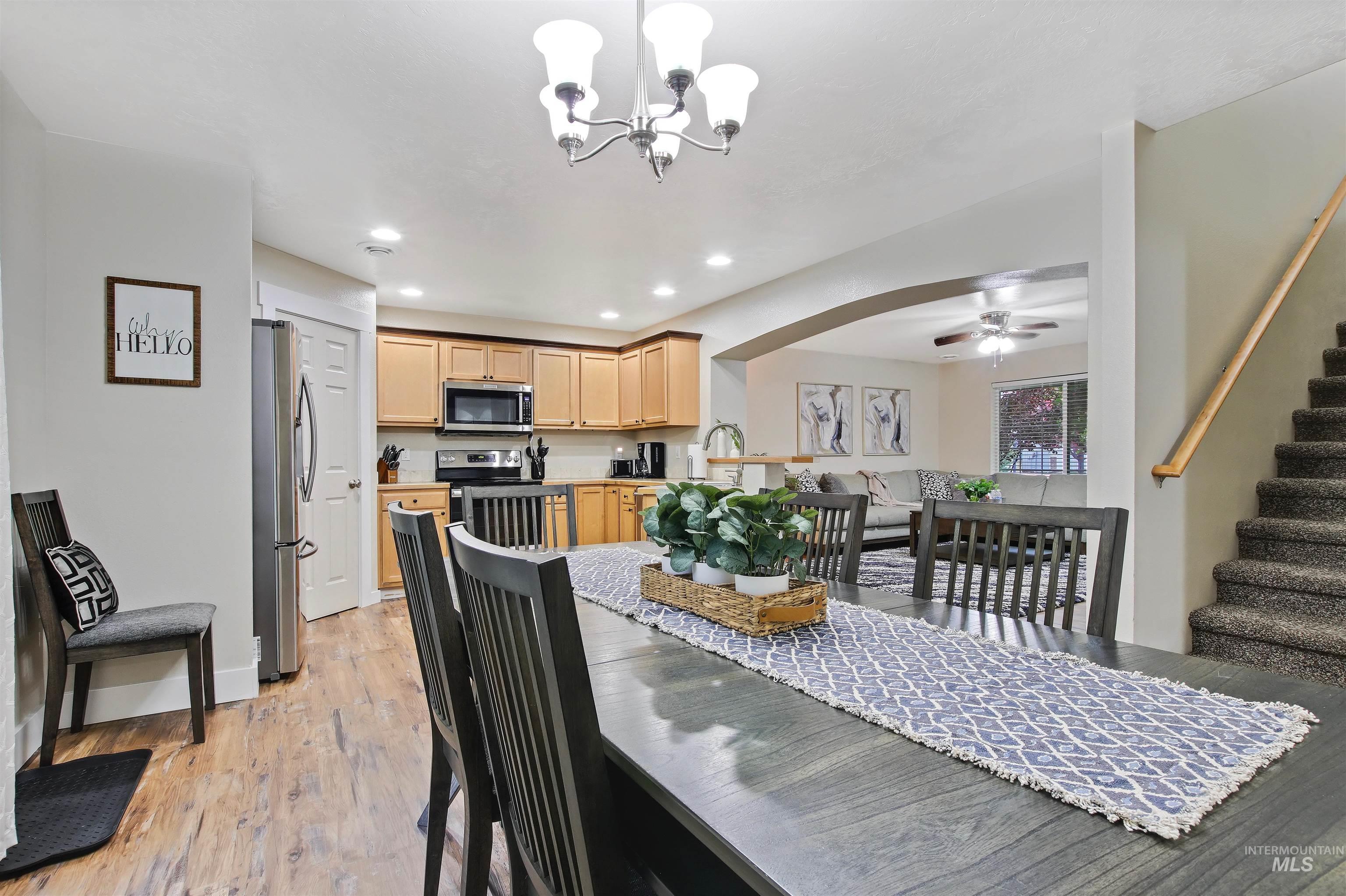 Dining space with stairway, a chandelier, light wood-style floors, arched walkways, and recessed lighting