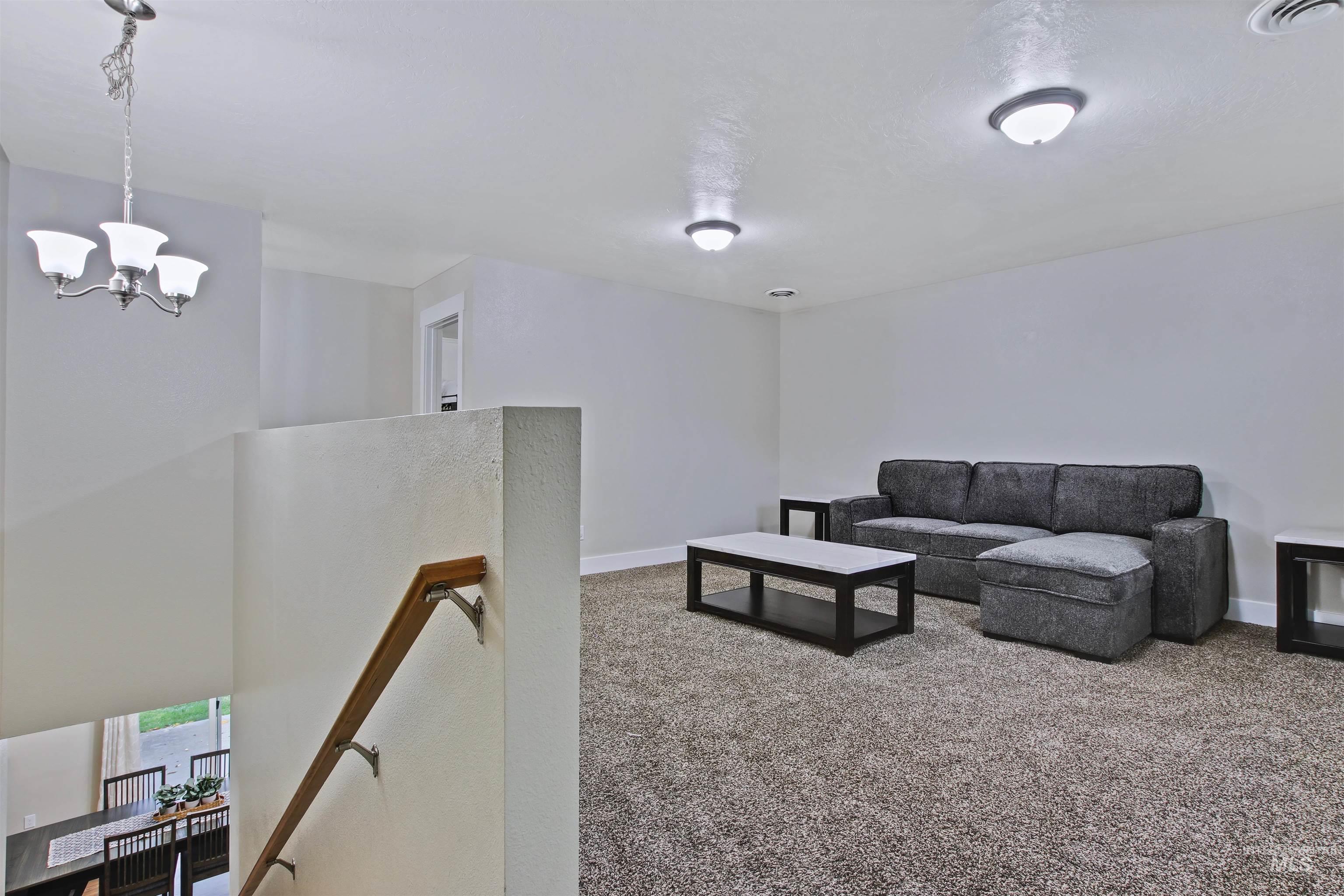 Living room featuring light carpet and a chandelier