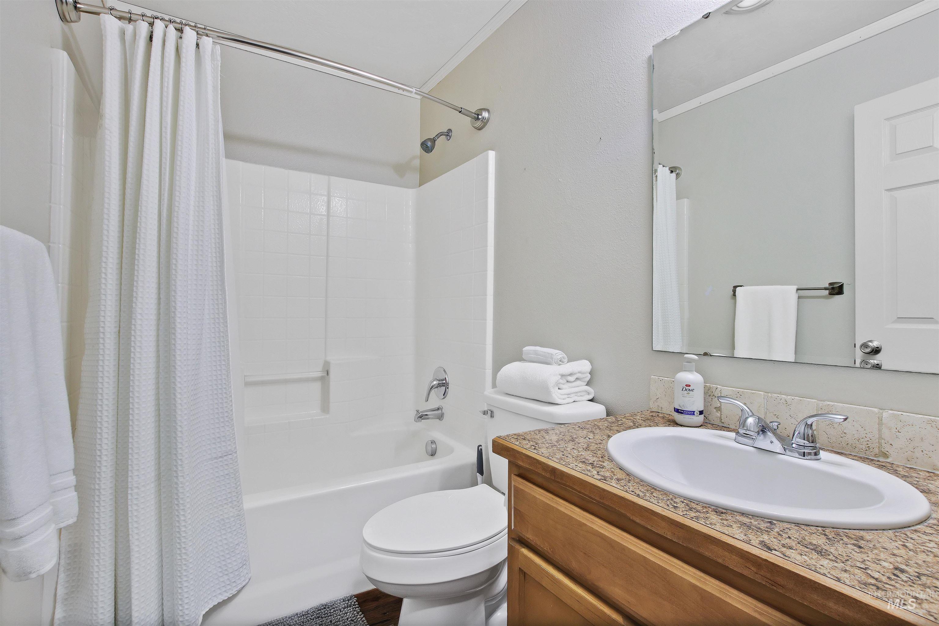 Full bathroom with shower / tub combo, vanity, and ornamental molding