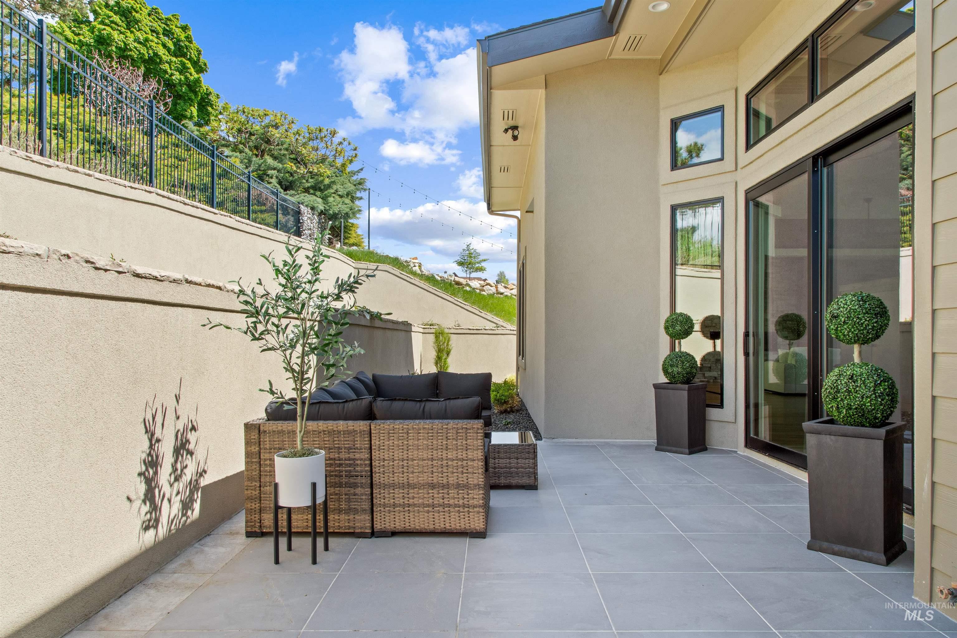Expansive outdoor patio featuring large format tile flooring, a stucco retaining wall, and direct access to the interior through a sliding glass door
