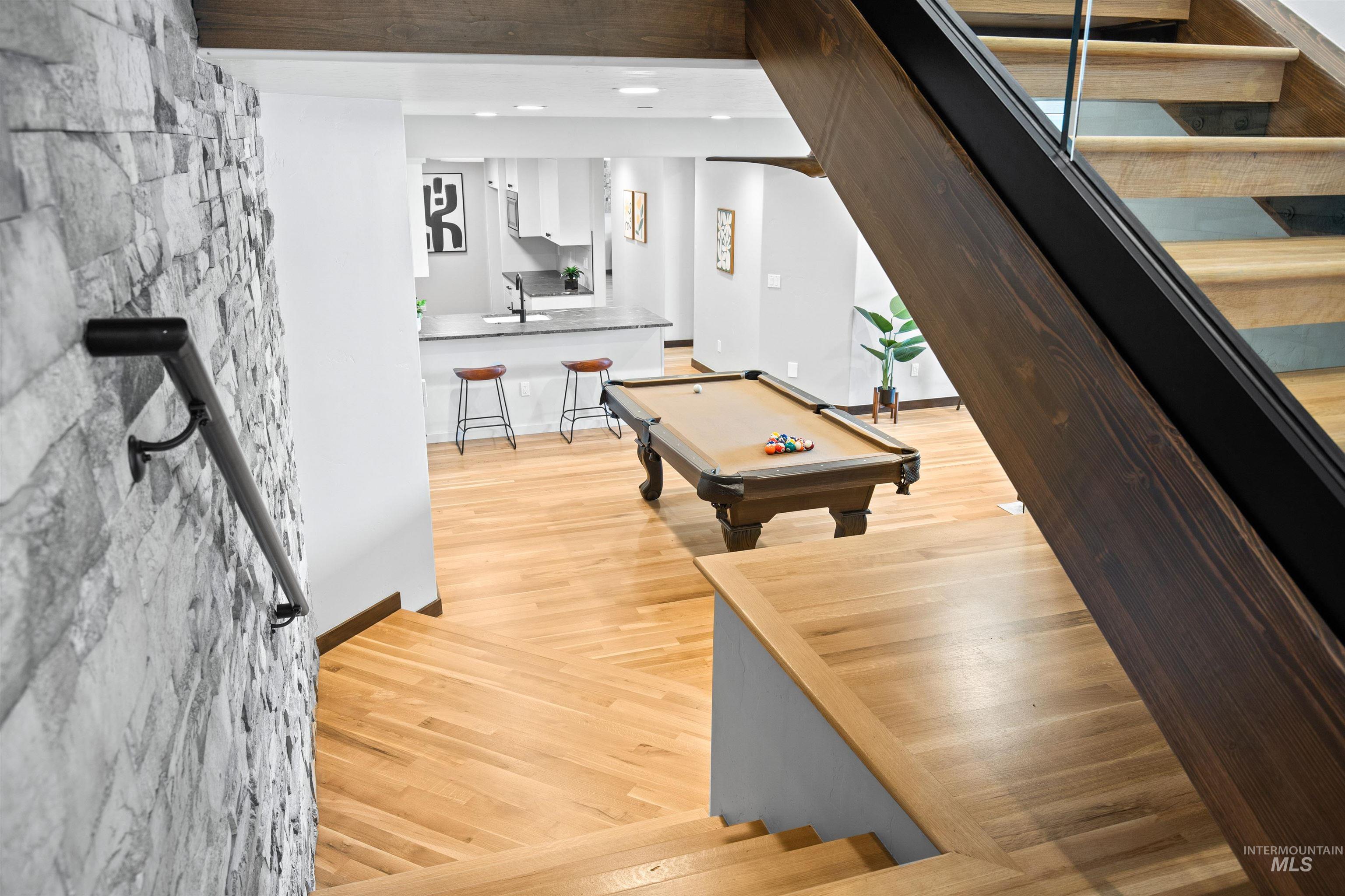 Modern staircase featuring wood treads, glass panel railing, and a stone accent wall