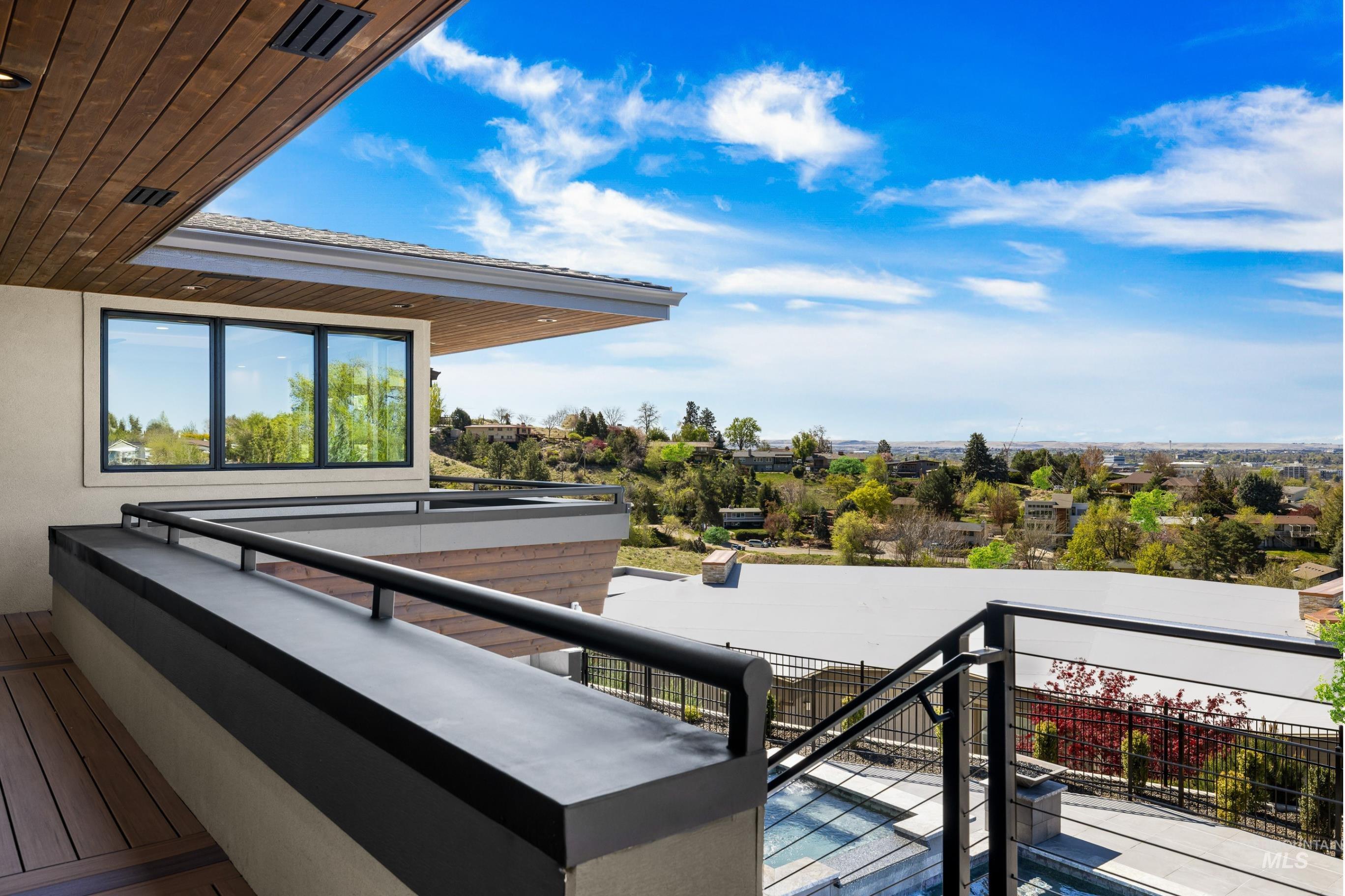 Exterior balcony featuring wood-finish decking, black metal railings, and an integrated window