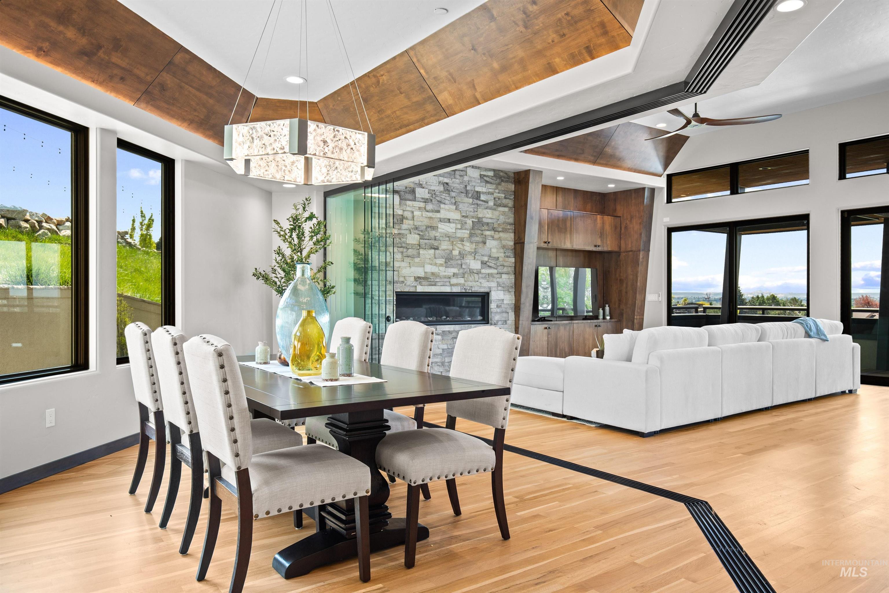 Open-concept living space featuring wood-finish flooring, a stone-clad fireplace with built-in cabinetry, and a coffered ceiling with integrated lighting