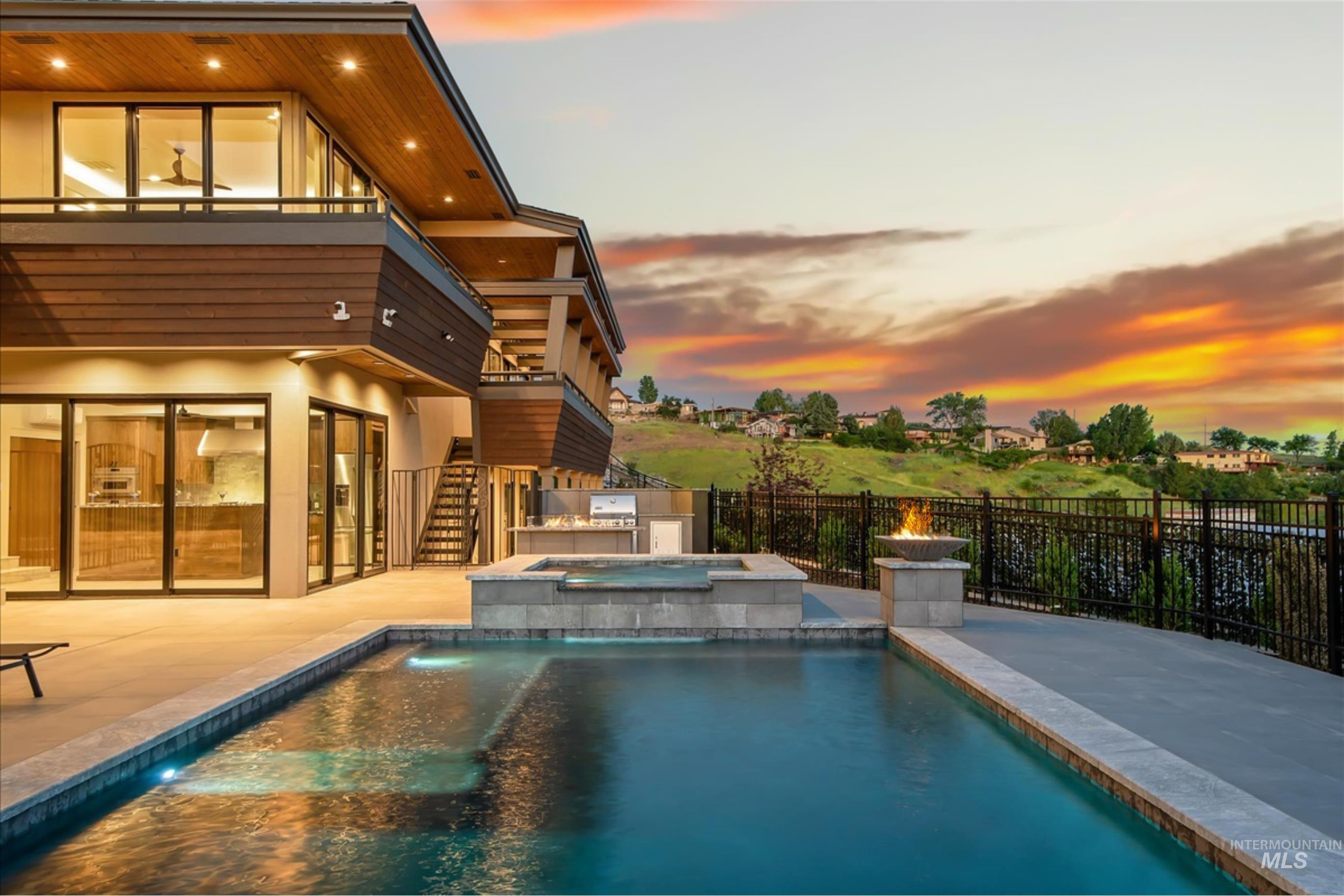 Contemporary multi-level residence featuring an integrated pool and spa, an outdoor kitchen, and a fire pit