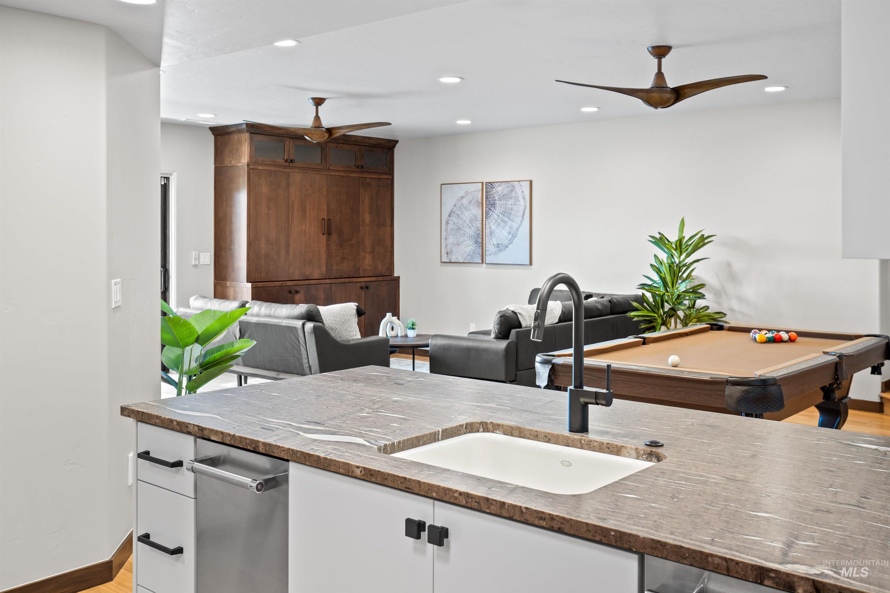 Kitchen island with a built-in sink, dark countertop, and integrated stainless steel dishwasher