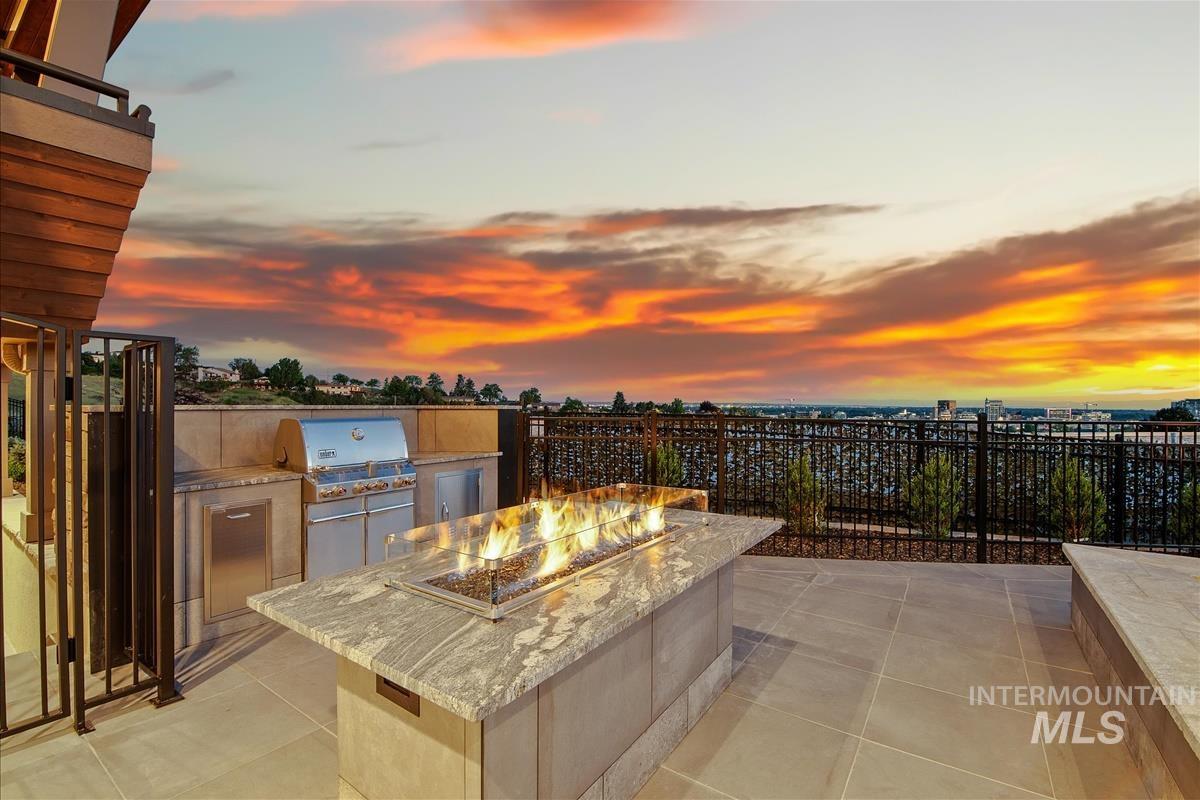 Outdoor patio featuring a built-in fire pit with a stone-finish countertop, a stainless steel grill, and an outdoor kitchen area with integrated cabinetry