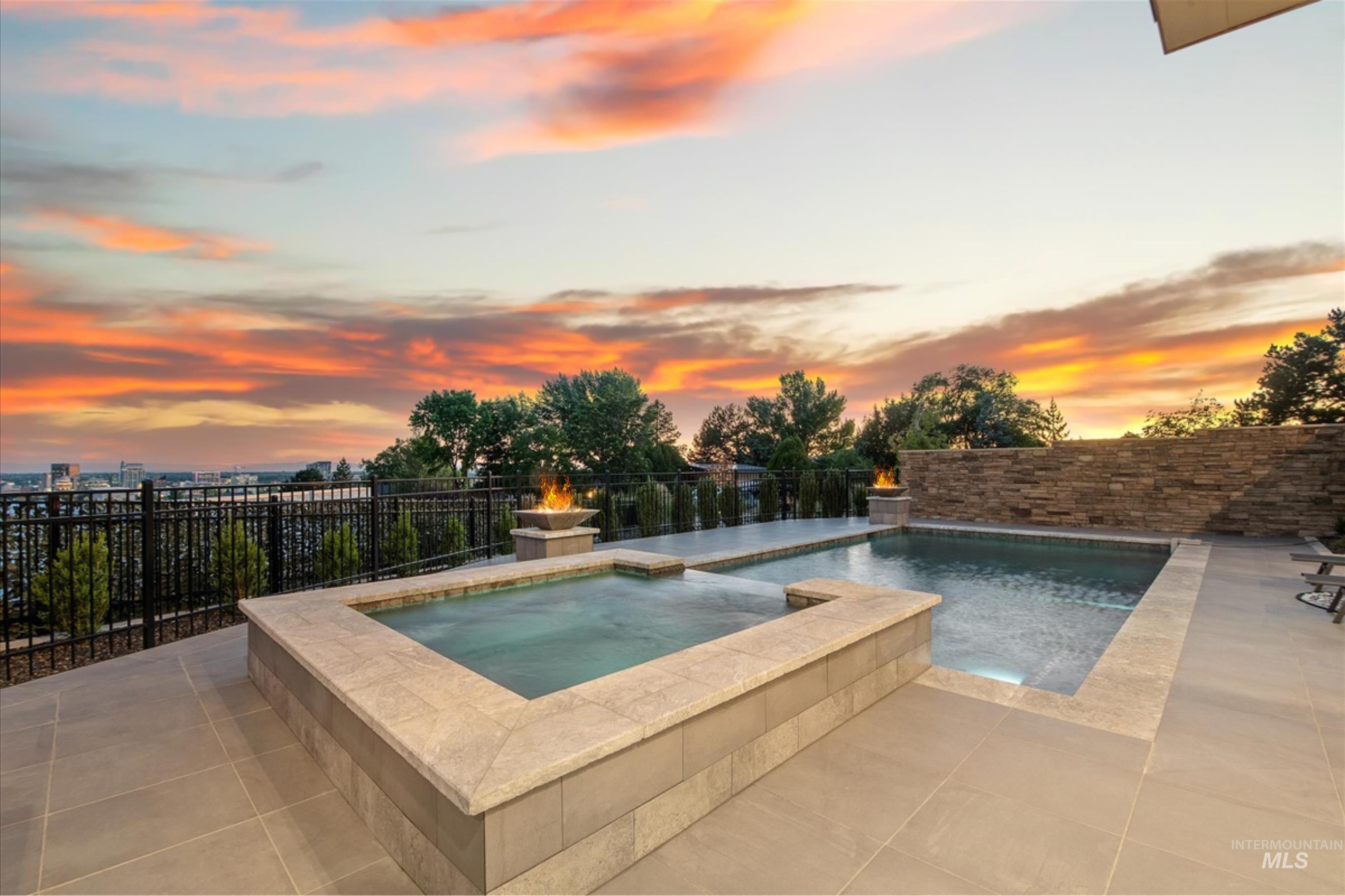 Expansive outdoor living area featuring a swimming pool, a separate spa, and surrounding tile patio