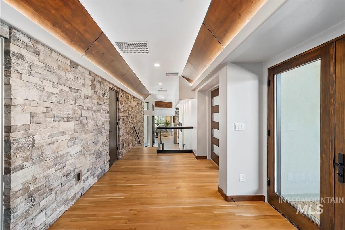 Hardwood flooring throughout featuring a stacked stone accent wall