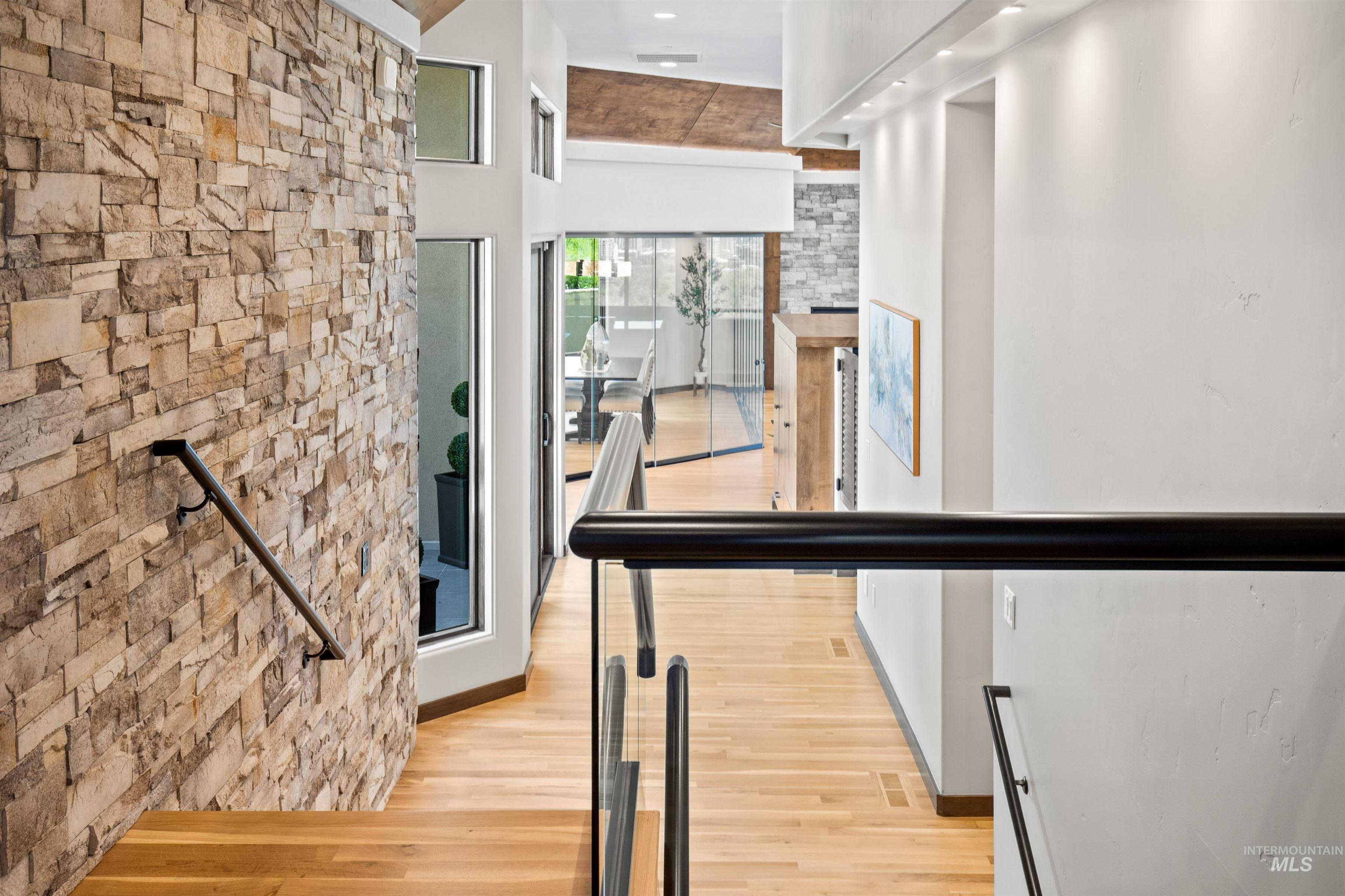 Stairway featuring a stone accent wall, wood-finish treads, and a black handrail