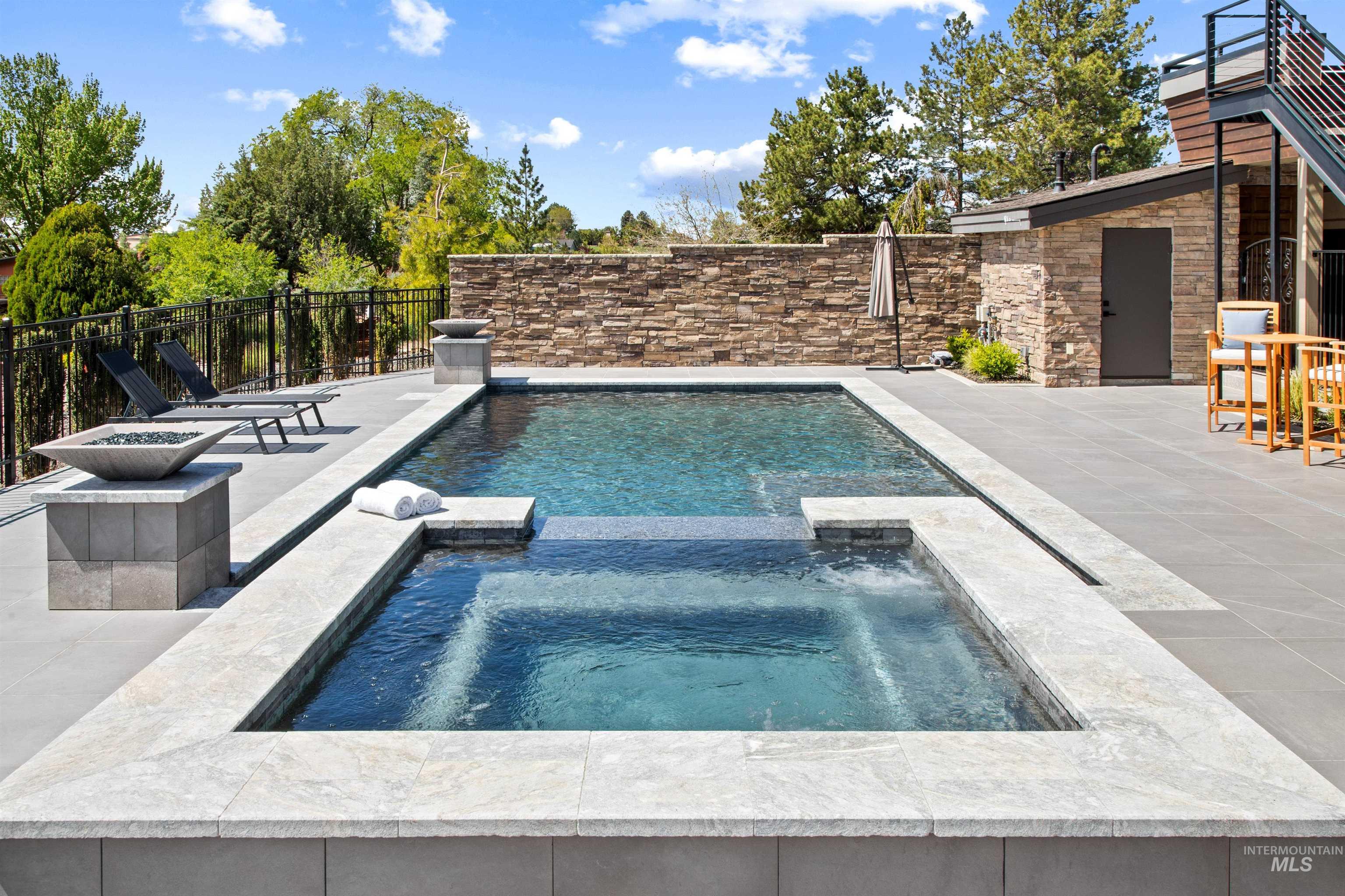 Rectangular swimming pool with integrated spa featuring light-colored coping