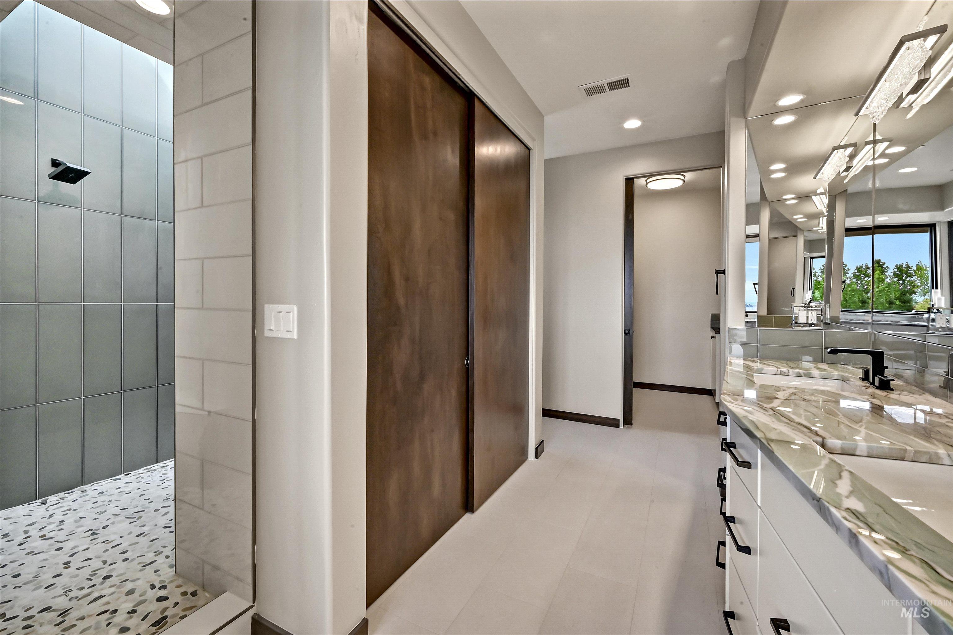 Contemporary bathroom featuring a spacious walk-in shower with pebble-finish flooring and subway tile