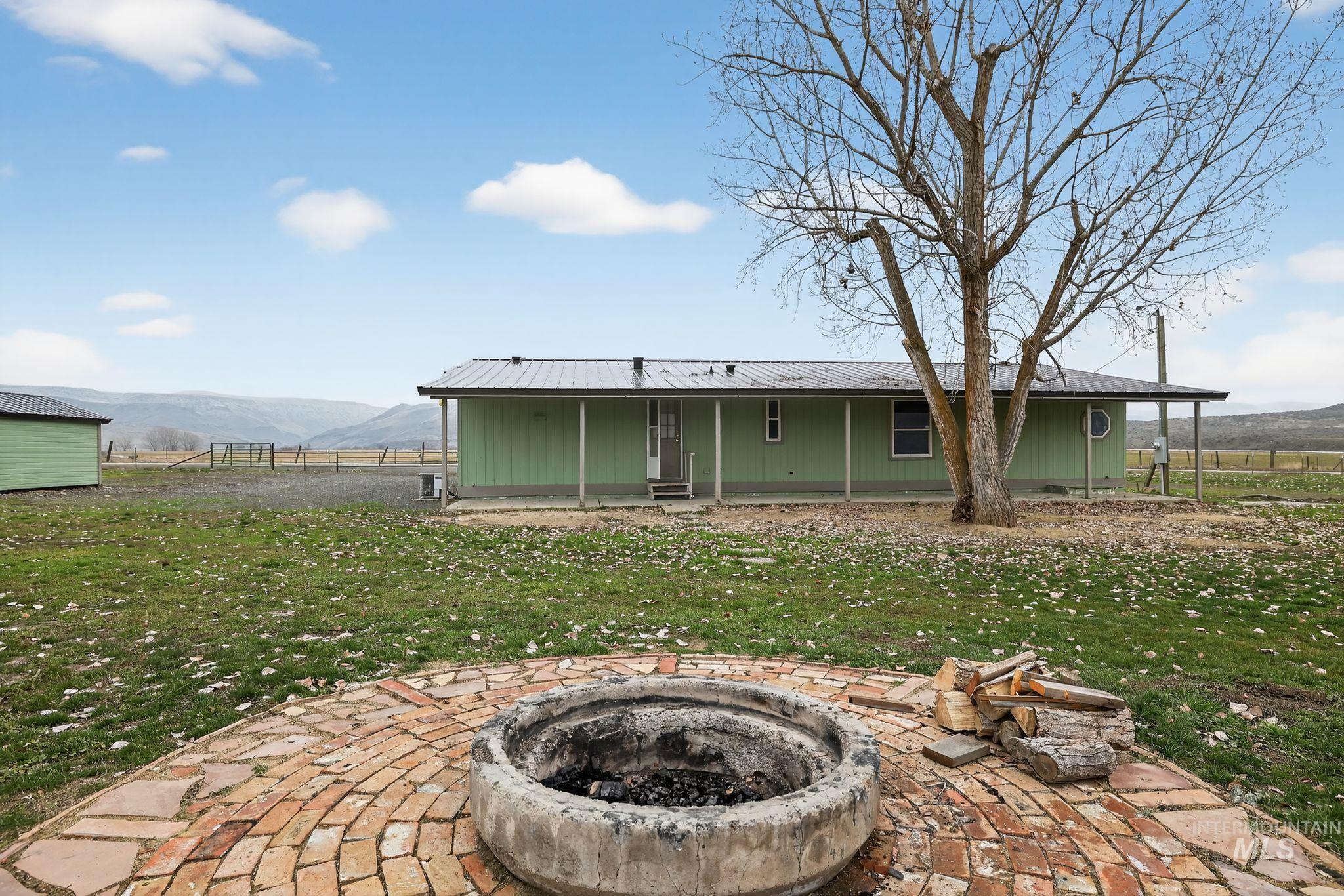 Back of house featuring a mountain view, a patio area, a metal roof, and a fire pit