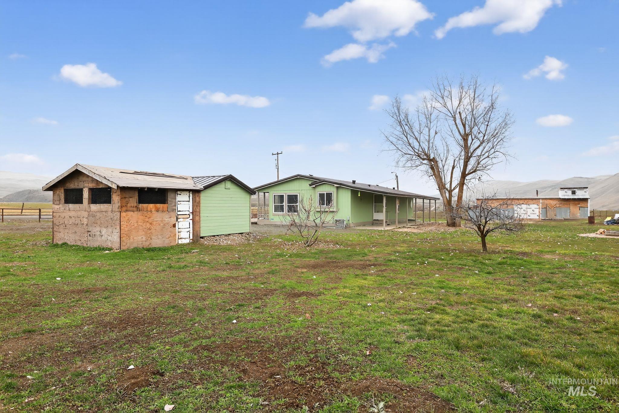 Back of house featuring an outbuilding, a lawn, and a mountain view