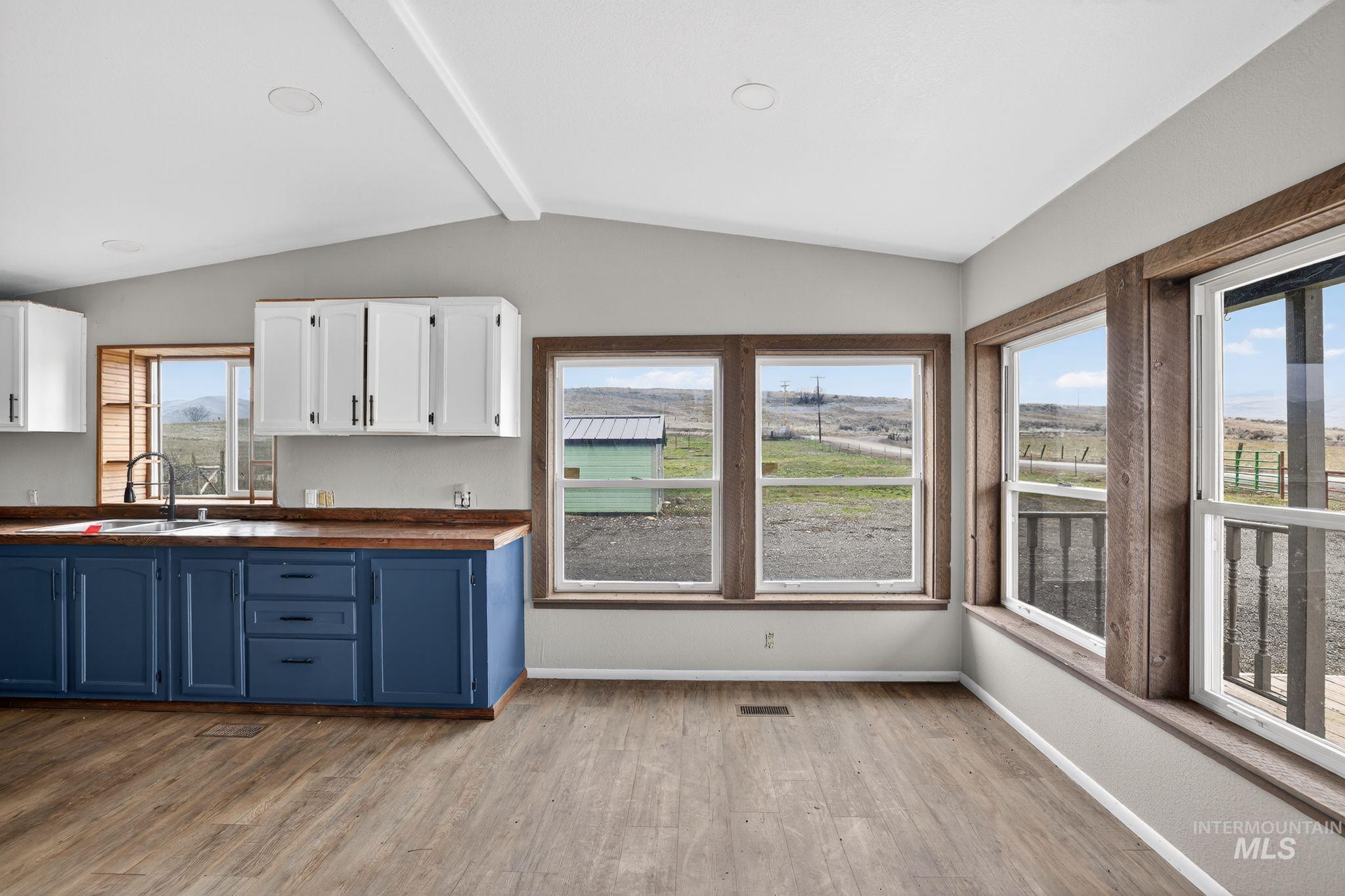 Kitchen featuring blue cabinets, white cabinetry, light wood-type flooring, and wooden counters
