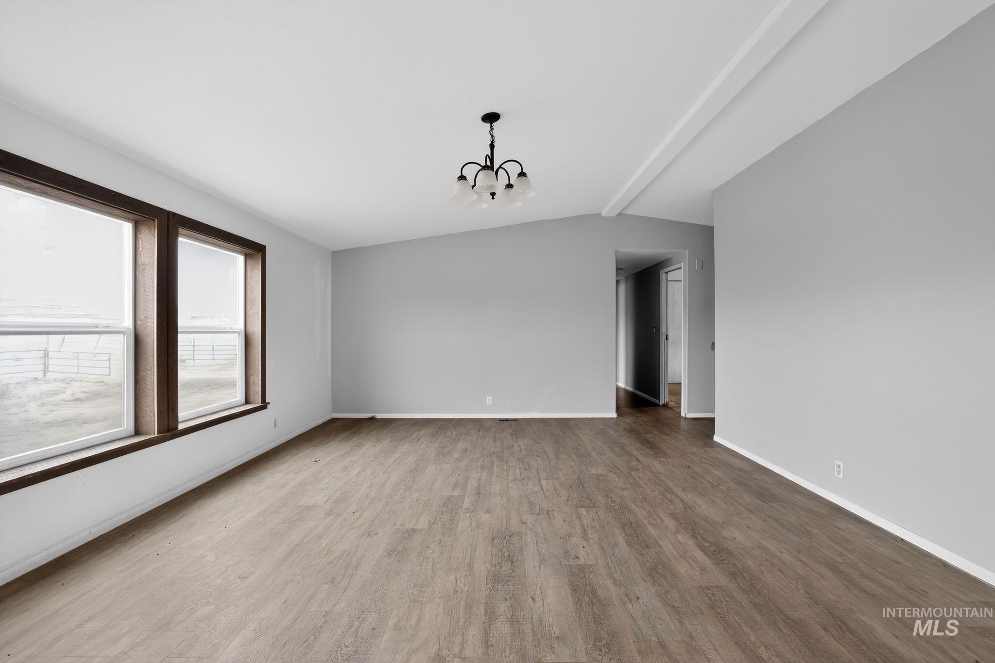 Spare room with a chandelier and light wood-type flooring