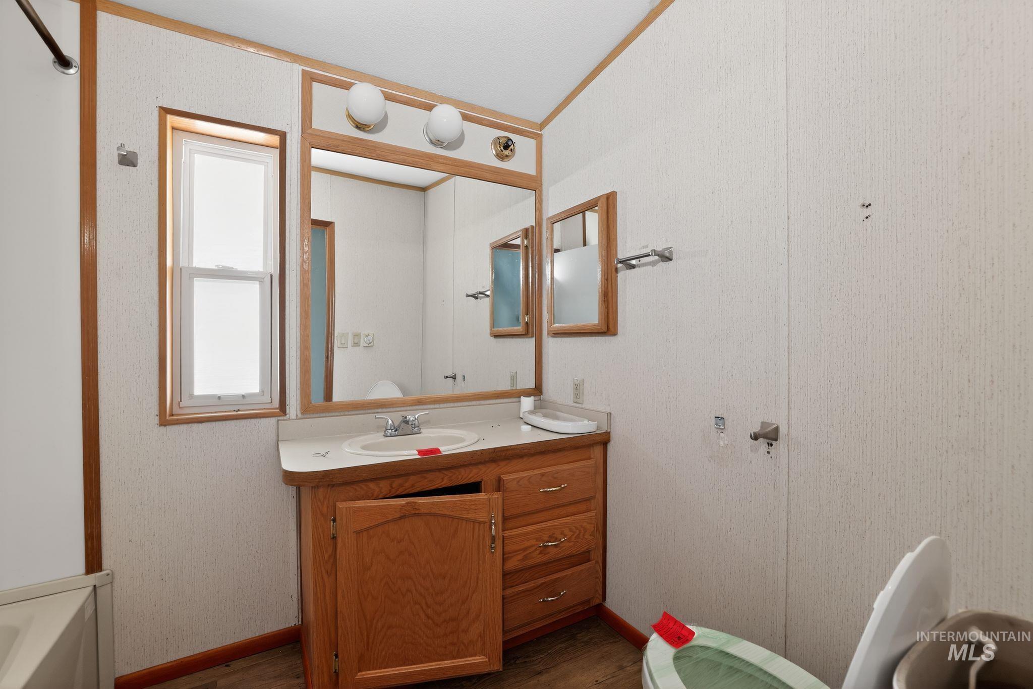 Bathroom with vanity, a tub to relax in, and dark wood-style flooring