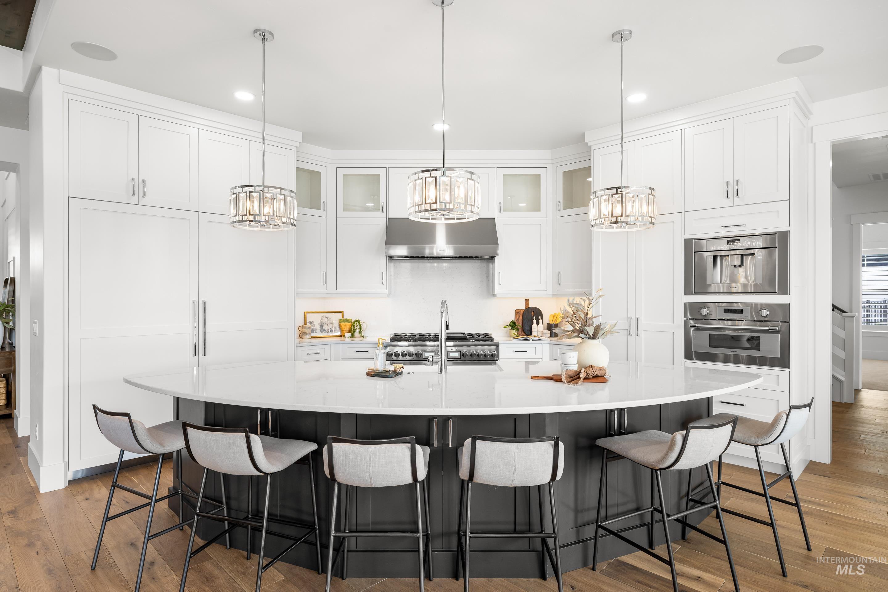 Kitchen with white cabinets, light wood-style flooring, a large island, a kitchen bar, and recessed lighting