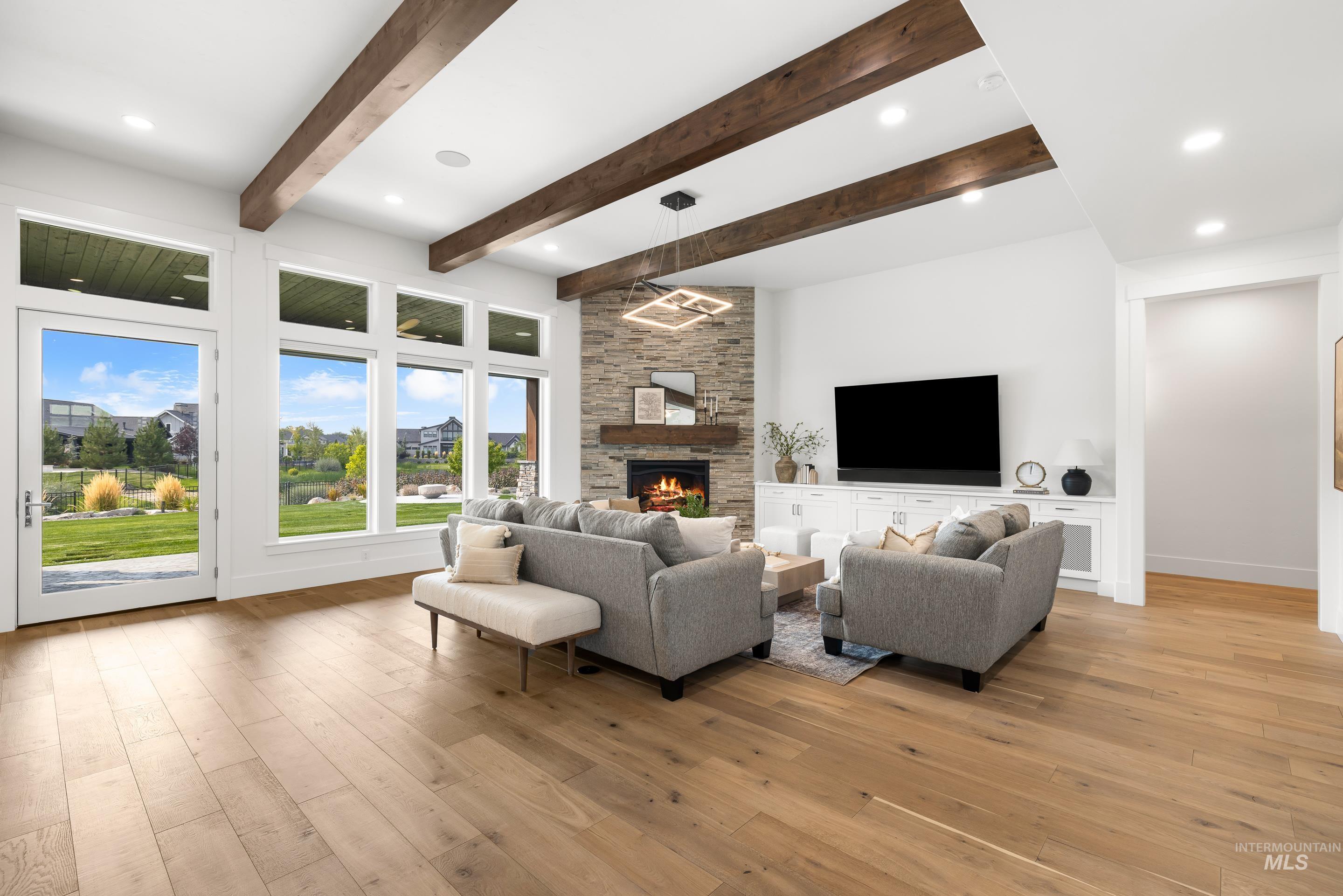 Living area featuring light wood finished floors, a fireplace, beamed ceiling, and recessed lighting