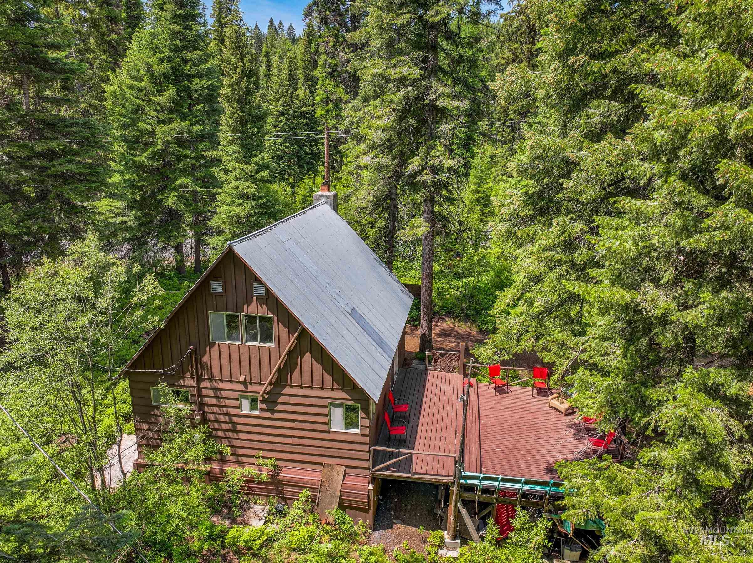 Back of property featuring board and batten siding, a wooded view, and a deck