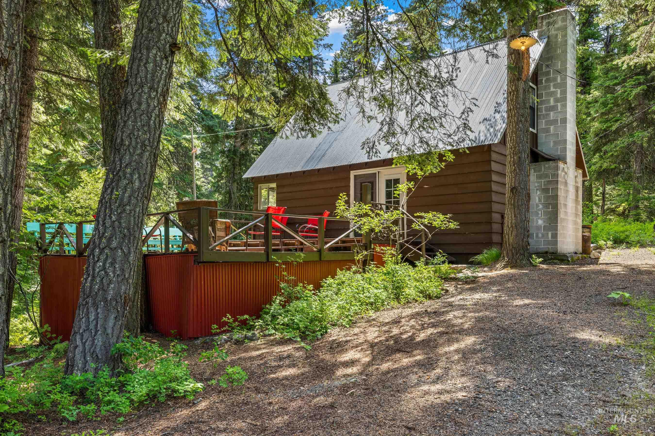 View of front of house featuring a wooden deck, a metal roof, and a chimney