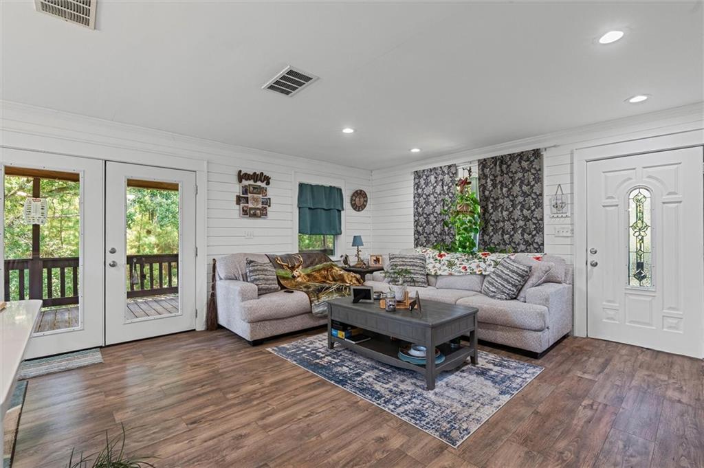 Living area featuring plenty of natural light, dark wood-type flooring, crown molding, recessed lighting, and french doors