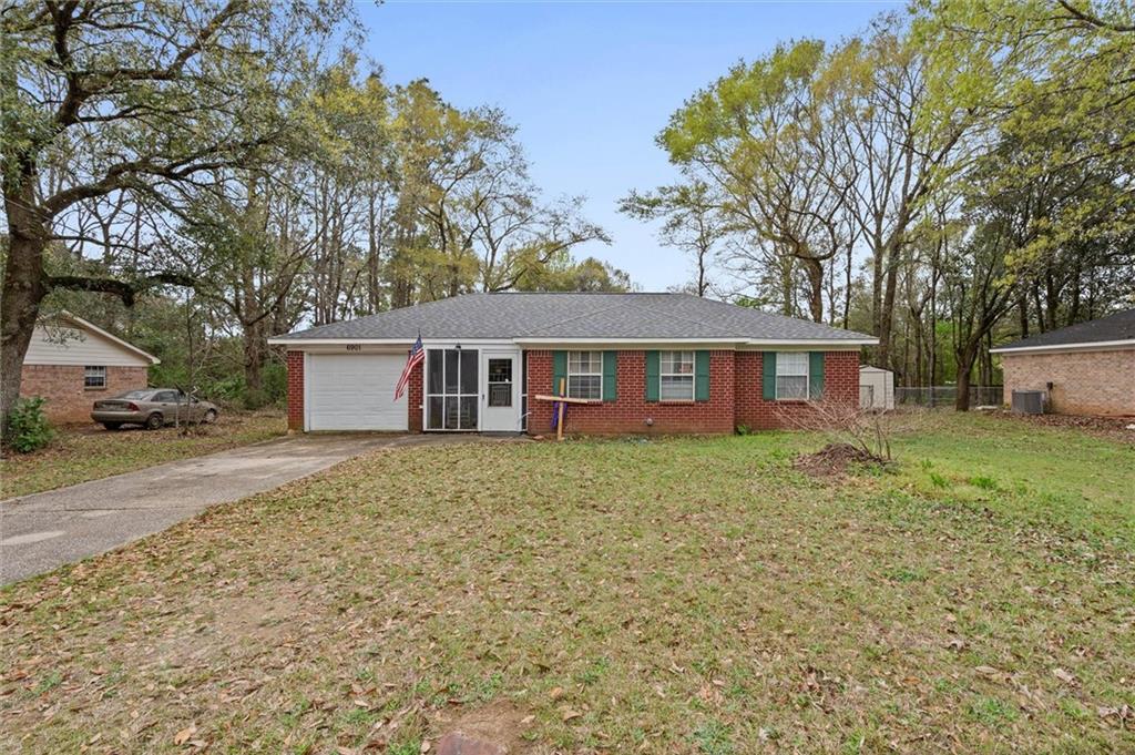 Ranch-style home with driveway, brick siding, an attached garage, and a front yard