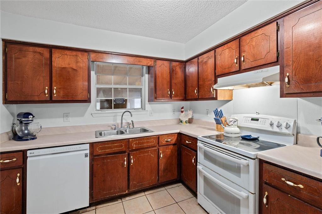 Kitchen with white appliances, light countertops, light tile patterned floors, and a textured ceiling