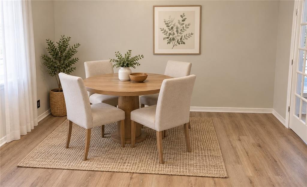 Living area featuring neutral wall tones, wood-finish flooring, and a white paneled entry door with an arched window insert