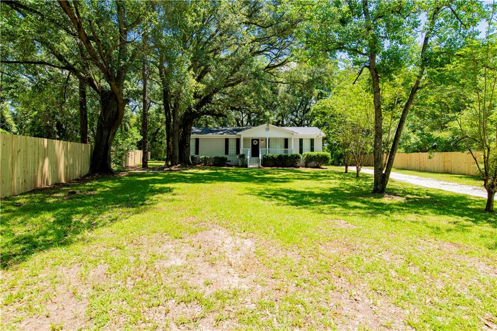 Exterior featuring a light gray brick facade, white columned front porch, dark entry door, and black window shutters