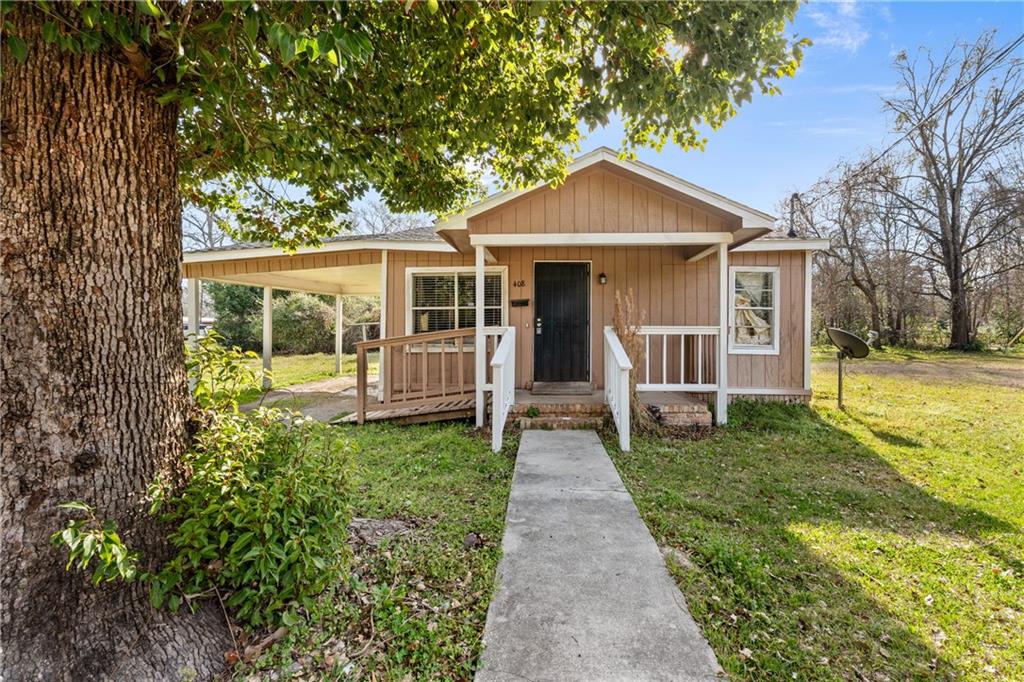 View of front facade with a front yard, a porch, and a carport