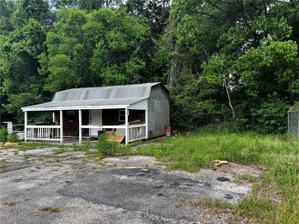 Single-story structure featuring a covered front porch with white railing, a gabled roof, and wood-panel siding