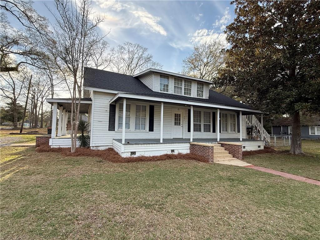 View of front of property with crawl space, roof with shingles, a large porch, and a front yard