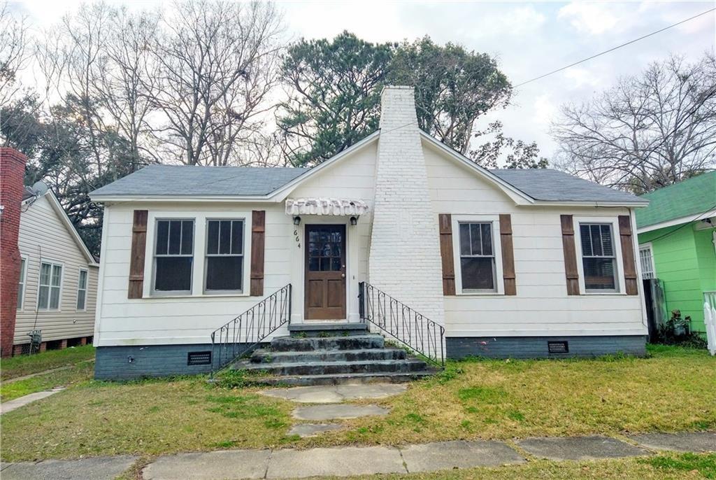 White siding exterior featuring a prominent brick chimney, wood shutters, and an awning over the front door
