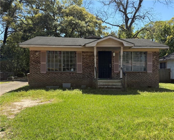 View of front facade featuring crawl space, brick siding, covered porch, a front yard, and a shingled roof