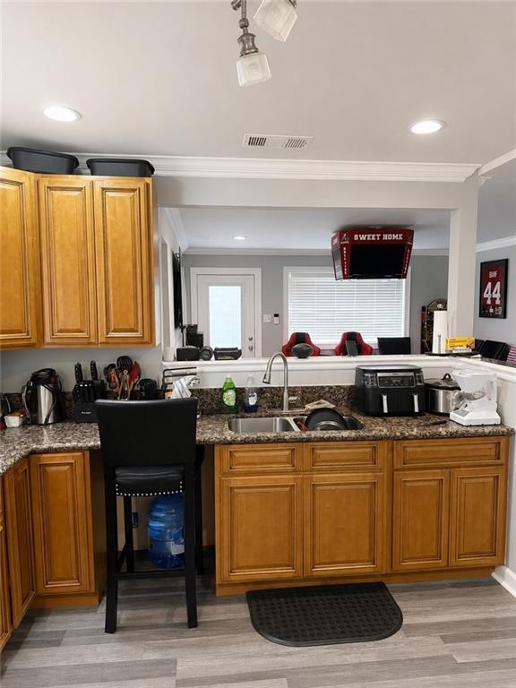 Kitchen featuring wood-finish cabinetry, granite-style countertops, a double basin sink with a high-arch faucet, and recessed lighting