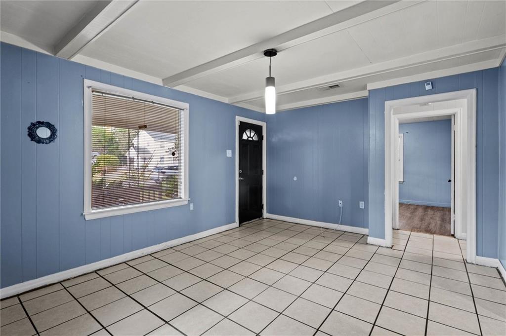 Foyer featuring beam ceiling, light tile patterned floors, and wood walls