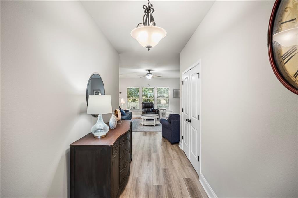 Hallway featuring wood-finish flooring, light neutral wall tones, and a dropped ceiling with recessed lighting