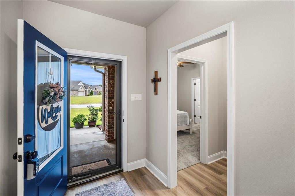 Foyer entrance featuring a blue door with glass insert, wood-finish flooring, and light gray wall paint