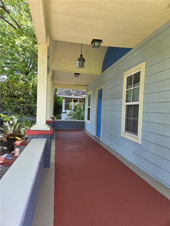 Expansive covered porch featuring a vibrant red-hued floor, light blue siding, and white trim