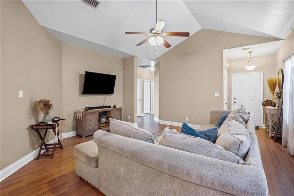 Living area featuring wood finished floors, vaulted ceiling, and a ceiling fan