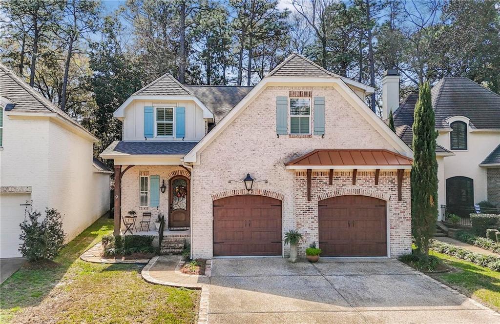 French provincial home with brick siding, a porch, concrete driveway, a shingled roof, and a front yard